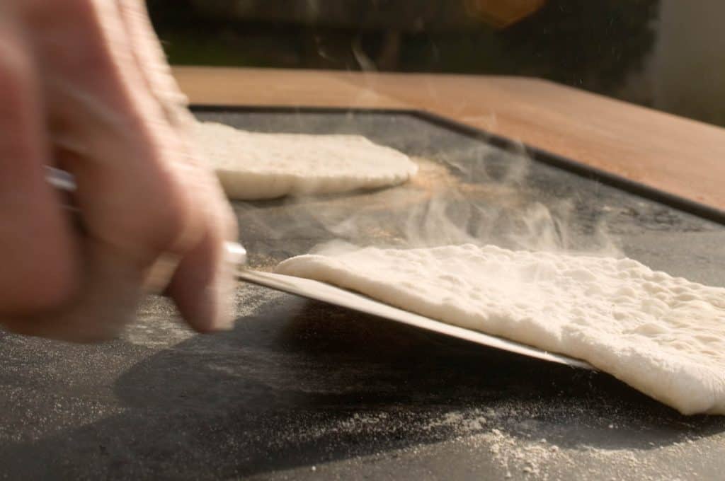 Kurt Gellner - Eine Person, die während eines Kochkurses mit einem Messer eine Pizza backt. - die Feuerstellen