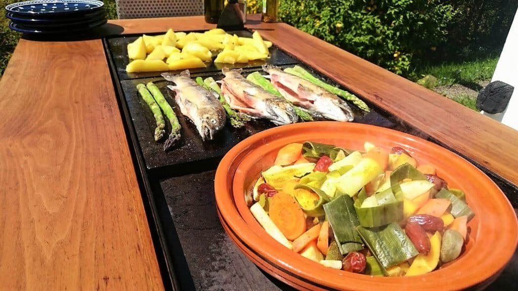 Ein Holztisch mit Essen darauf, darunter ein Kochkurs Fisch.