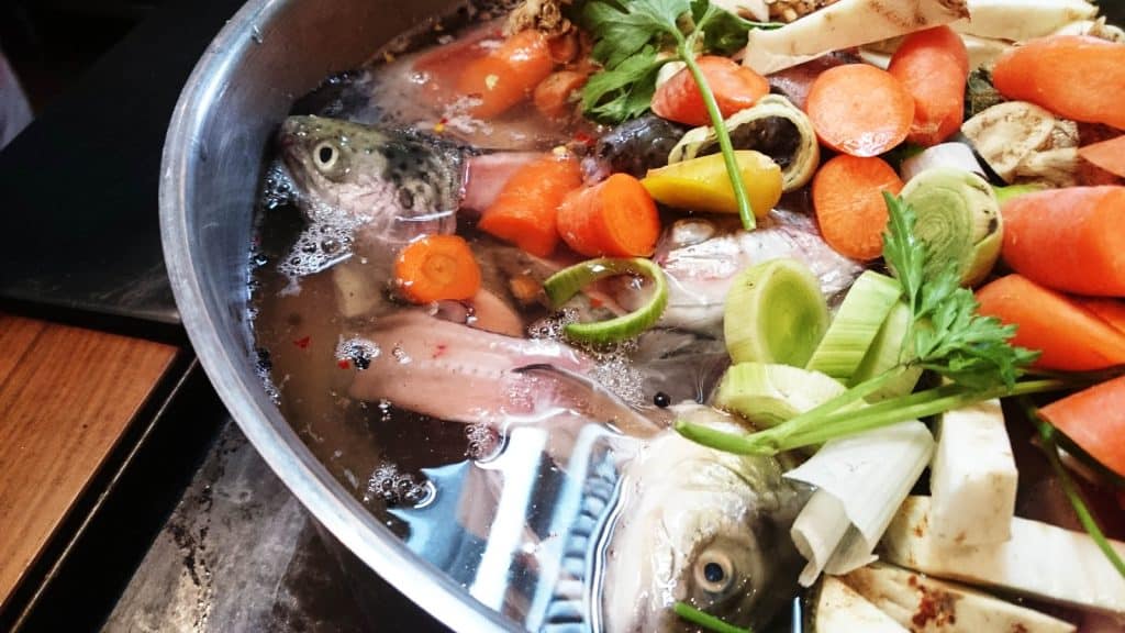 Ein Fischkochkurs-Topf mit Fisch und Gemüse.