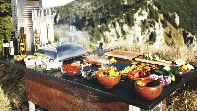 Holzfeuerküche mit Essen darauf vor einem Berg.