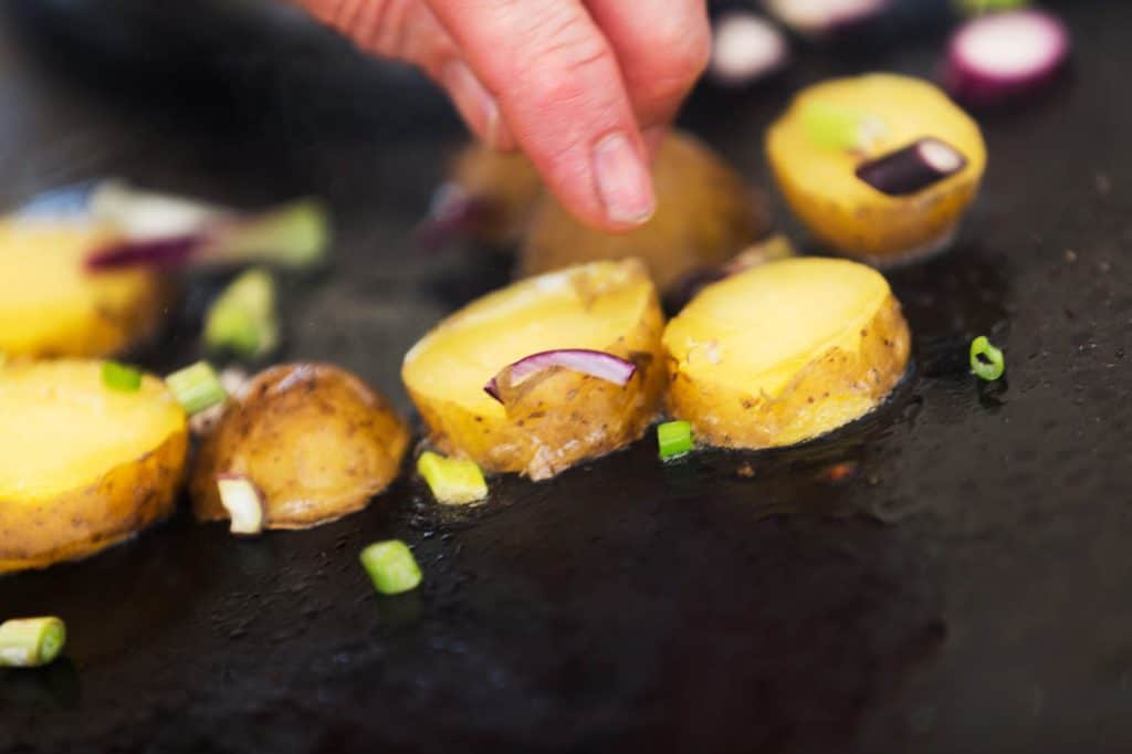 Eine Person schneidet Kartoffeln in einem veganen Kochkurs.