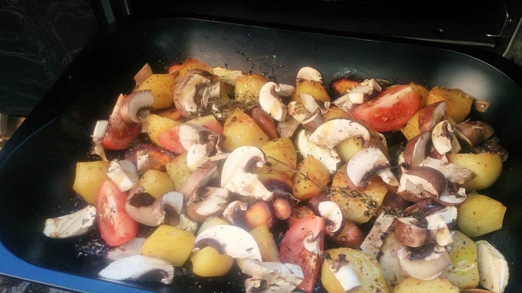 Eine vegane Pfanne mit Kartoffeln, Pilzen und Tomaten darin.